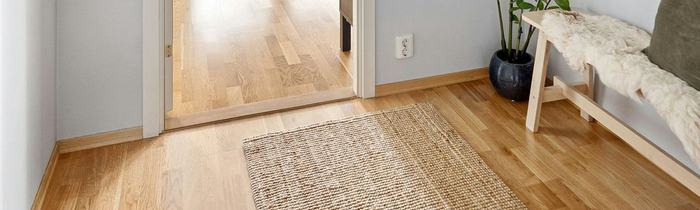 Close view of light wood flooring, a transition and an adjacent room